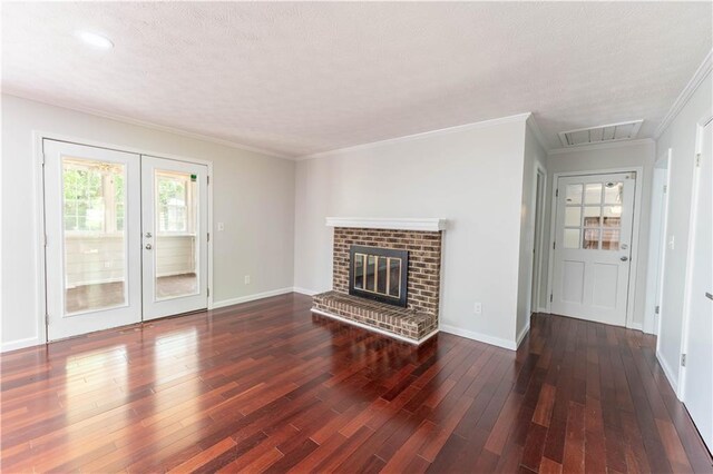 unfurnished living room with french doors, hardwood / wood-style floors, baseboards, crown molding, and a brick fireplace