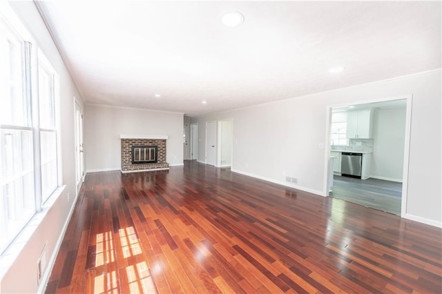 unfurnished living room featuring dark wood-style flooring, a brick fireplace, baseboards, and recessed lighting