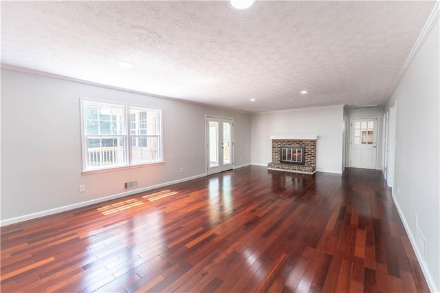 unfurnished living room featuring a textured ceiling, plenty of natural light, dark wood-style flooring, baseboards, and ornamental molding