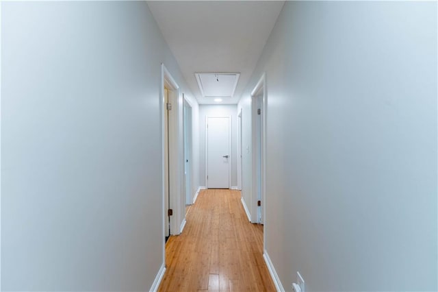 corridor with attic access, baseboards, and light wood-style flooring