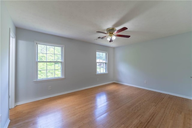 spare room with ceiling fan, light wood-style floors, and baseboards