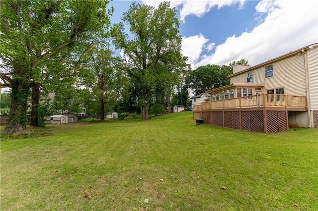 view of green lawn with a storage shed, a deck, and an outdoor structure