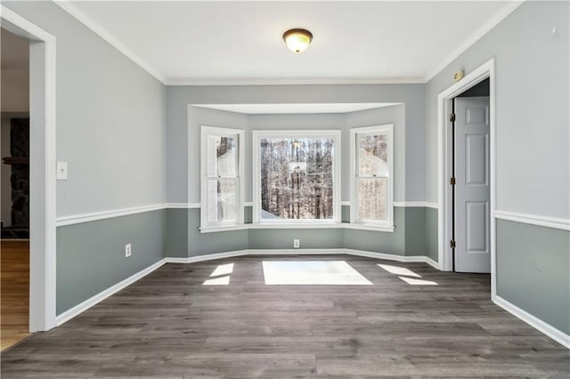 spare room featuring baseboards, wood finished floors, and crown molding