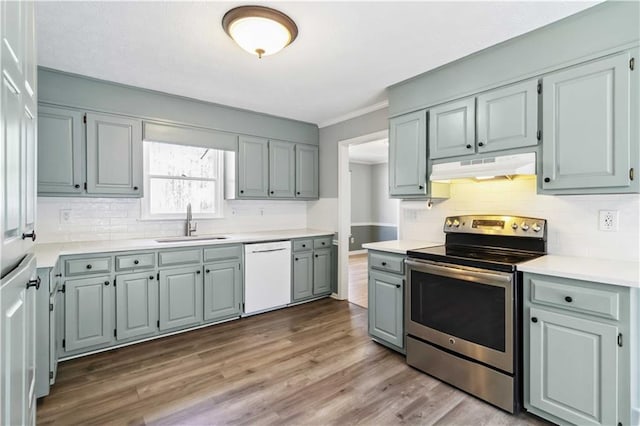 kitchen with under cabinet range hood, dishwasher, stainless steel electric range oven, wood finished floors, and a sink