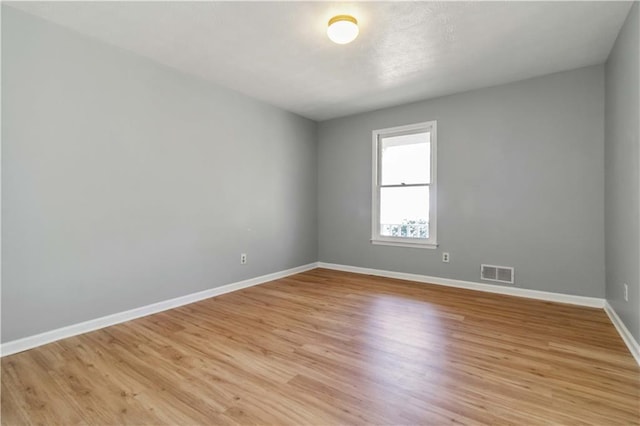 unfurnished room with baseboards, visible vents, and light wood finished floors