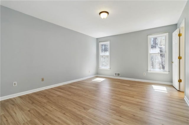 unfurnished room featuring visible vents, light wood-type flooring, and baseboards