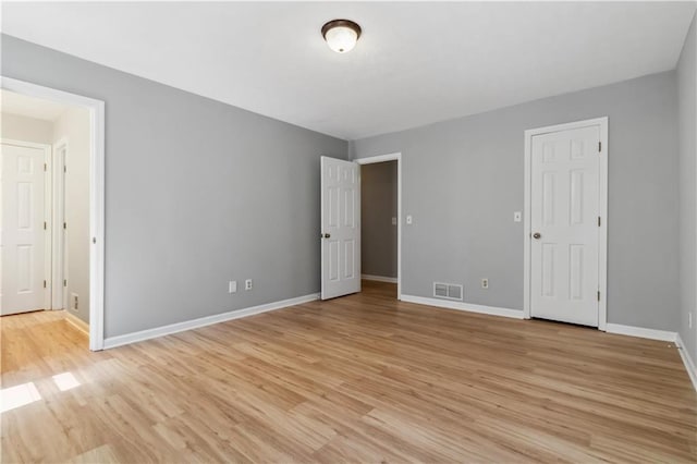 unfurnished bedroom featuring light wood finished floors, visible vents, and baseboards