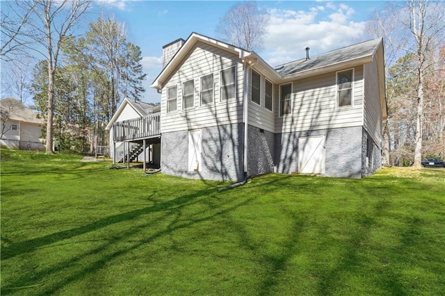 rear view of house featuring stairs, a lawn, a chimney, a deck, and a garage