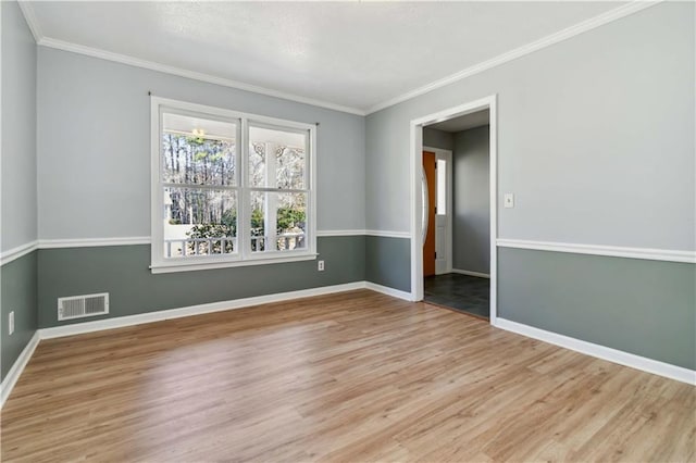 empty room with visible vents, crown molding, baseboards, and wood finished floors