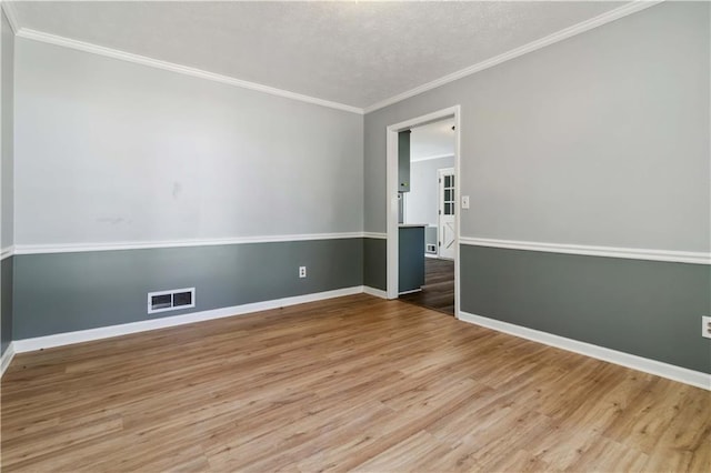 spare room featuring visible vents, crown molding, baseboards, and wood finished floors