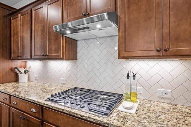 7143 Lake Edge Dr, Flowery Branch, GA 30542 - kitchen with stainless steel gas cooktop, light stone countertops, under cabinet range hood, and decorative backsplash