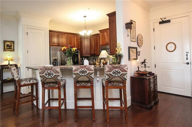 kitchen with pendant lighting, dark wood-type flooring, stainless steel appliances, a kitchen bar, and kitchen peninsula