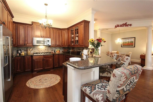 kitchen with stainless steel appliances, an inviting chandelier, and ornate columns