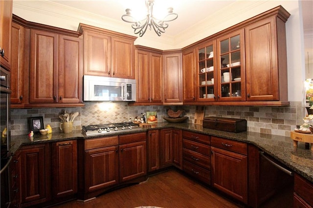 kitchen featuring dark stone countertops, stainless steel appliances, decorative backsplash, dark hardwood / wood-style flooring, and decorative light fixtures