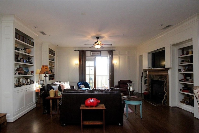 living room with ceiling fan, built in features, dark hardwood / wood-style flooring, and a fireplace