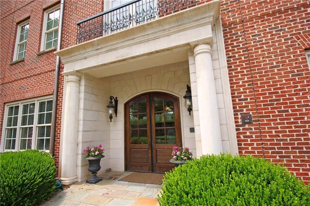 view of exterior entry featuring french doors and a balcony