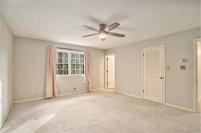 carpeted spare room featuring ceiling fan and a textured ceiling