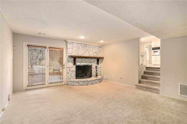 unfurnished living room with a fireplace, carpet floors, and a textured ceiling