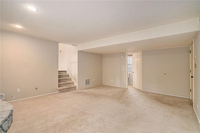 basement featuring light carpet and a textured ceiling