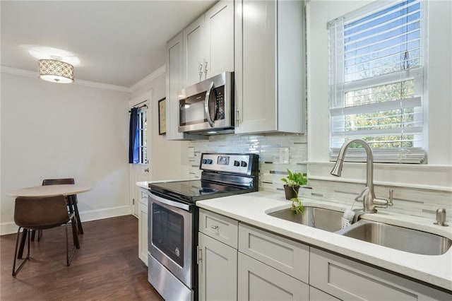 kitchen featuring appliances with stainless steel finishes, sink, white cabinets, decorative backsplash, and ornamental molding