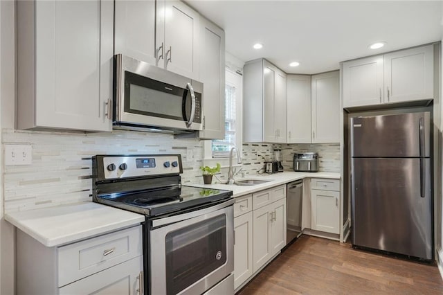 kitchen featuring appliances with stainless steel finishes, dark hardwood / wood-style flooring, sink, and backsplash