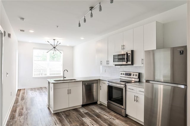 kitchen featuring visible vents, a peninsula, light countertops, a sink, and appliances with stainless steel finishes