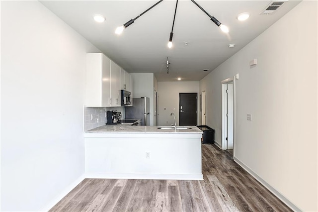 kitchen with visible vents, a peninsula, light countertops, a sink, and stainless steel appliances