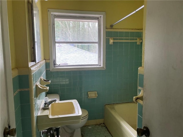 bathroom featuring tile patterned flooring, a sink, tile walls, and toilet