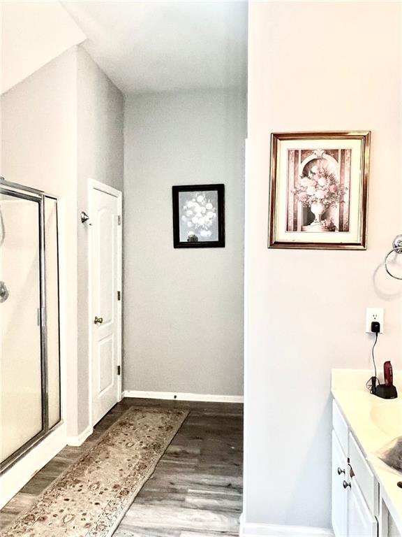 bathroom with vanity, hardwood / wood-style flooring, and a shower with door