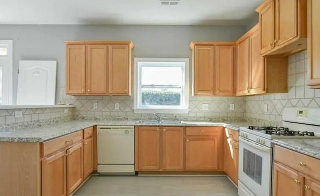 kitchen featuring white appliances, light stone counters, tasteful backsplash, and sink