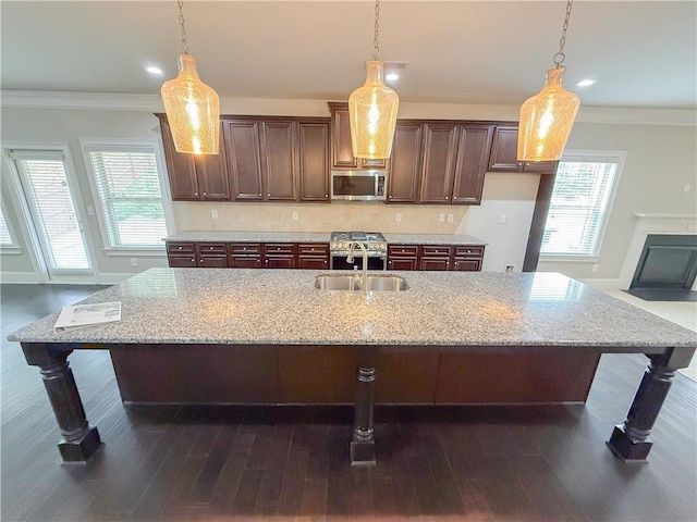 kitchen featuring sink, decorative light fixtures, and a center island with sink