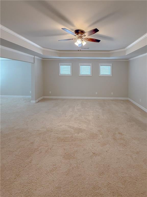 carpeted spare room featuring ornamental molding, a raised ceiling, and ceiling fan