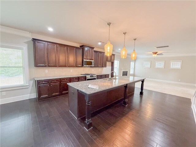 kitchen with a breakfast bar, decorative light fixtures, sink, stainless steel appliances, and dark brown cabinets