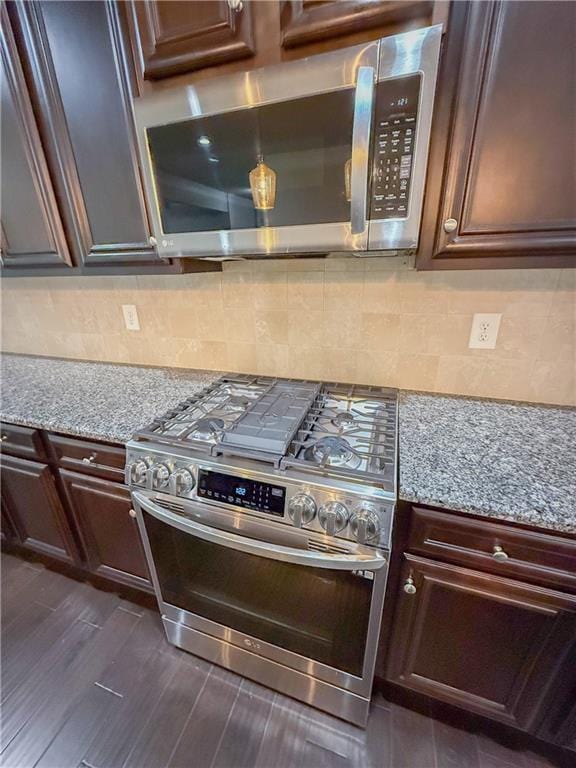 kitchen with stainless steel appliances, light stone countertops, dark hardwood / wood-style floors, and backsplash