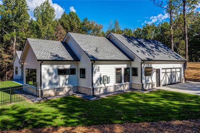 back of house with fence, an attached garage, a lawn, and a shingled roof