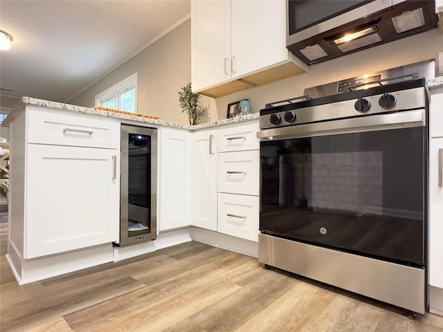 kitchen featuring appliances with stainless steel finishes, light wood-type flooring, wine cooler, white cabinets, and light stone counters