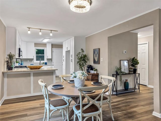 dining room featuring sink, an inviting chandelier, ornamental molding, and hardwood / wood-style floors