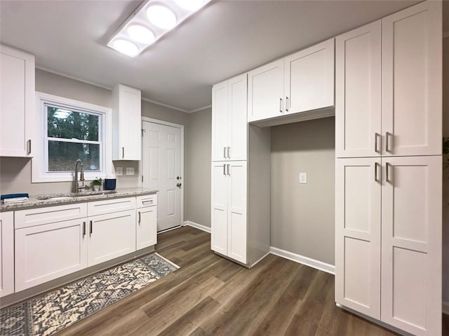 kitchen with light stone countertops, sink, and white cabinetry