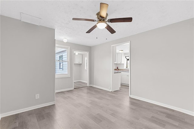 unfurnished room featuring a textured ceiling, ceiling fan, and light hardwood / wood-style flooring