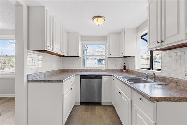 kitchen featuring white cabinetry, light hardwood / wood-style floors, sink, stainless steel dishwasher, and tasteful backsplash