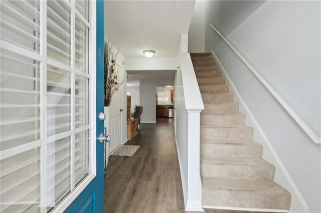 stairs with wood-type flooring and a textured ceiling