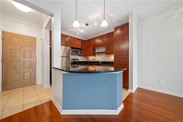 kitchen featuring appliances with stainless steel finishes, a kitchen island, light hardwood / wood-style floors, decorative light fixtures, and decorative backsplash