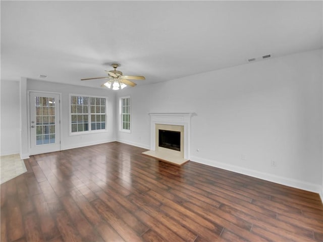 unfurnished living room with visible vents, dark wood finished floors, baseboards, ceiling fan, and a fireplace