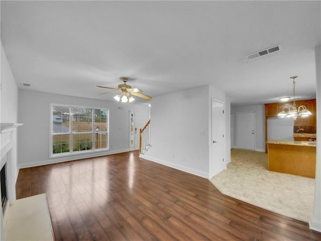 unfurnished living room featuring dark wood-style flooring, stairway, a fireplace with flush hearth, and visible vents