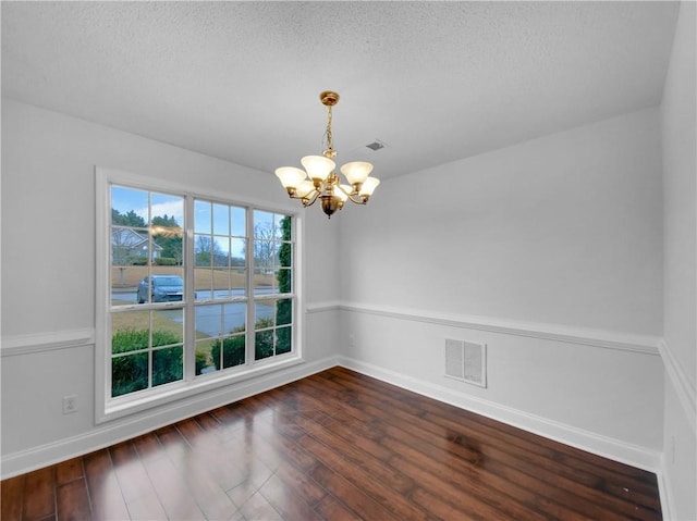 unfurnished room with dark wood-style floors, visible vents, baseboards, and an inviting chandelier