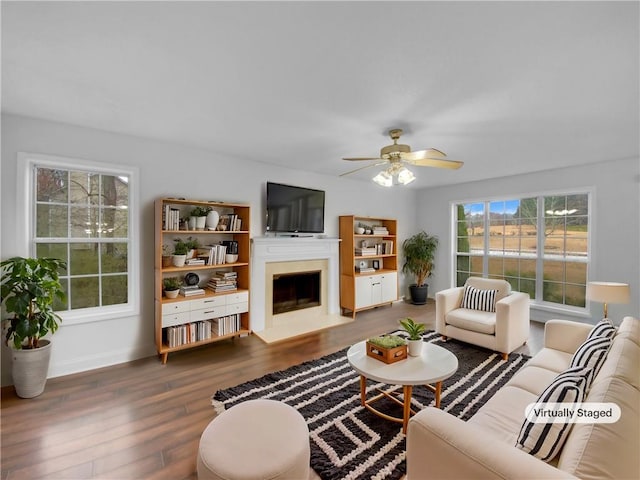 living room featuring a fireplace, wood finished floors, a ceiling fan, and baseboards