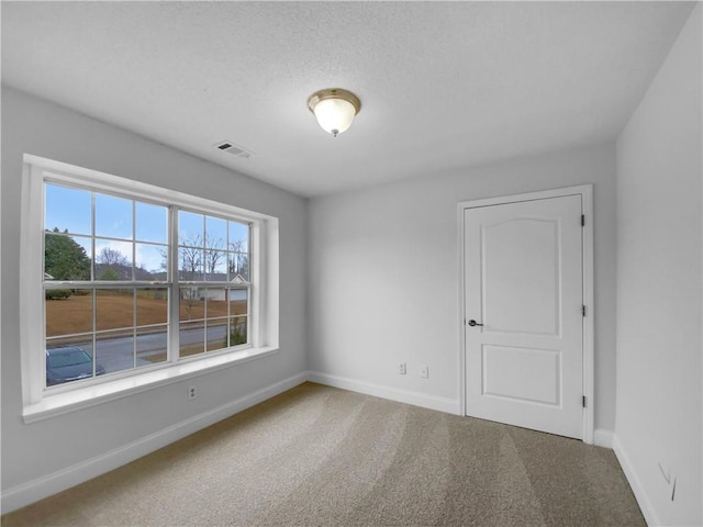 empty room with carpet flooring, visible vents, and baseboards