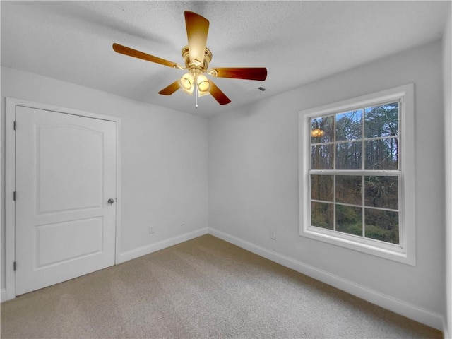 carpeted spare room with a ceiling fan, visible vents, and baseboards