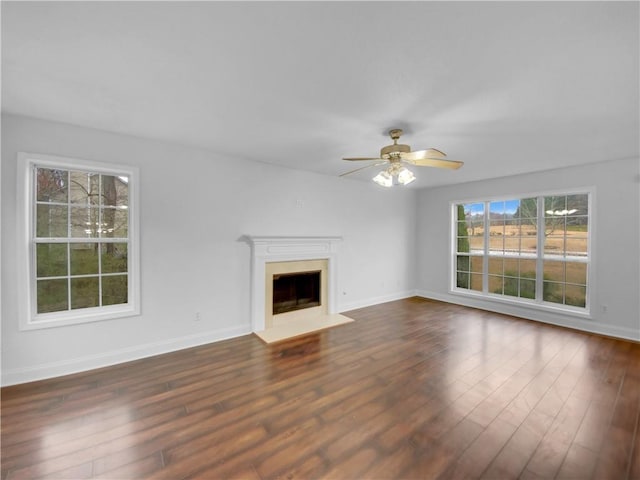 unfurnished living room featuring a fireplace, dark wood finished floors, a ceiling fan, and baseboards