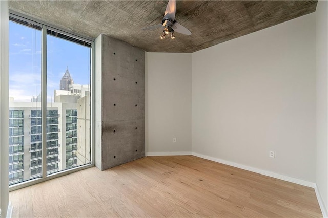 855 Peachtree St NE Unit 3205, Atlanta, GA 30308 - spare room with wood finished floors, ceiling fan, a city view, a wall of windows, and baseboards